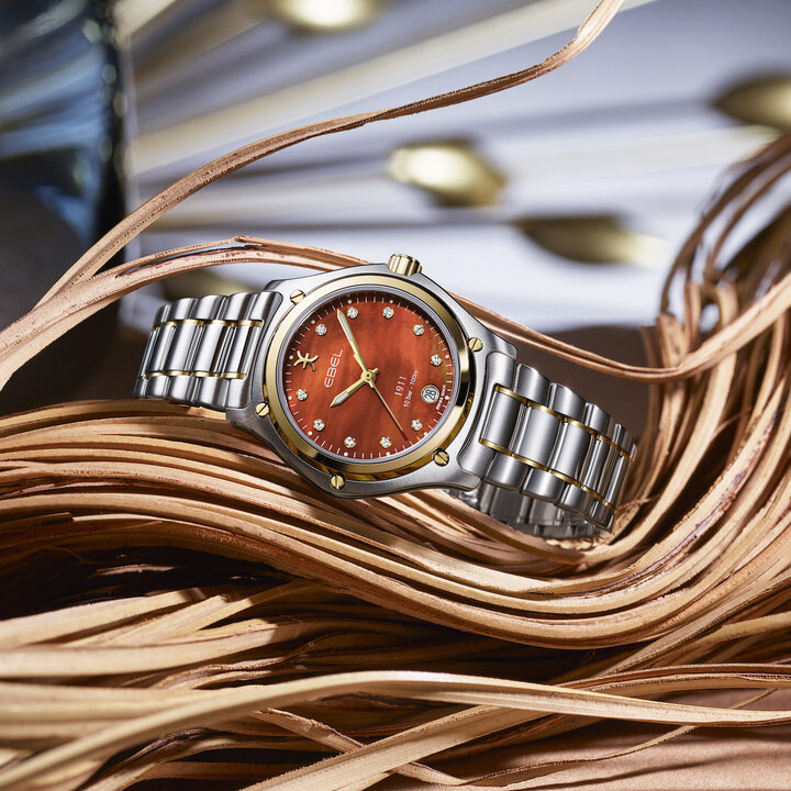 L'Ebel 1911 Grande bicolore arbore un cadran en nacre ocre et une lunette en or jaune 18 carats.