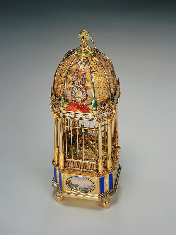 Cage à trois oiseaux chanteurs, avec montre et sonnerie Rochat Frères(Genève, 1810-1835), horlogers et facteurs de musique Genève, vers 1814 Cage octogonale en or jaune et rose, polis, gravés, ciselés, émail peint sur or, sous fondant, cristaux facettés, émail champlevé, base en cuivre doré Sonnerie au passage des quarts sur deux cloches, les oiseaux s'animent et sifflent au passage de l'heure et sur demande Haut. 27.1, larg. 10.1, prof. 10.1 cm Ville de Genève, Musée d'art et d'histoire, Achat, 2003 Inv. H 2003-136